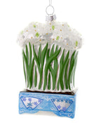 A glass ornament in the form of a chinoiserie planter holding blooming paperwhite narcissus.