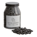 Jar of black river stones with a label on a white background
