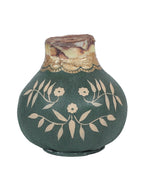 an unsprouted waxed amaryllis bulb covered in hand painted designs. Base color is sage green, with gold leaves and flowers all around the bulb. 
