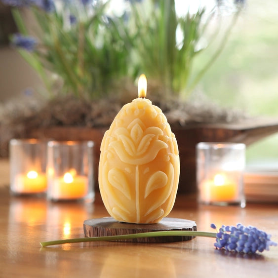 Egg shaped sculptured beeswax pillar candle with tulips and leaves.