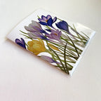 The Crocus Notecard featuring watercolor crocus blooms in shades of purple, violet, and gold printed on linen-textured cardstock, blank inside with envelope.