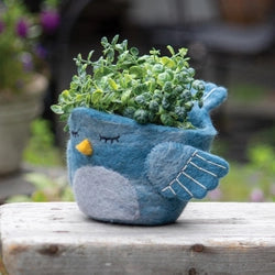 A woolen hand felted pot cover in the form of a sleepy blue bird.