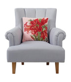 A woolen needle hook throw pillow in pink featuring red amaryllis blossoms and foliage.