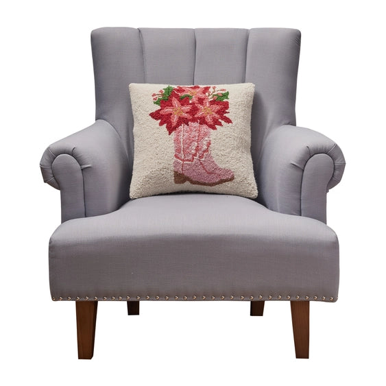 A woolen needle hook throw pillow featuring pink cowboy boots filled with red amaryllis flowers.