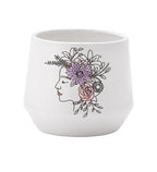 The Purple Flower Crown Ceramic Pot features a minimalist white design with a line-drawn woman's profile, accented by purple, pink, and green floral details—an elegant and artistic planter for any space.