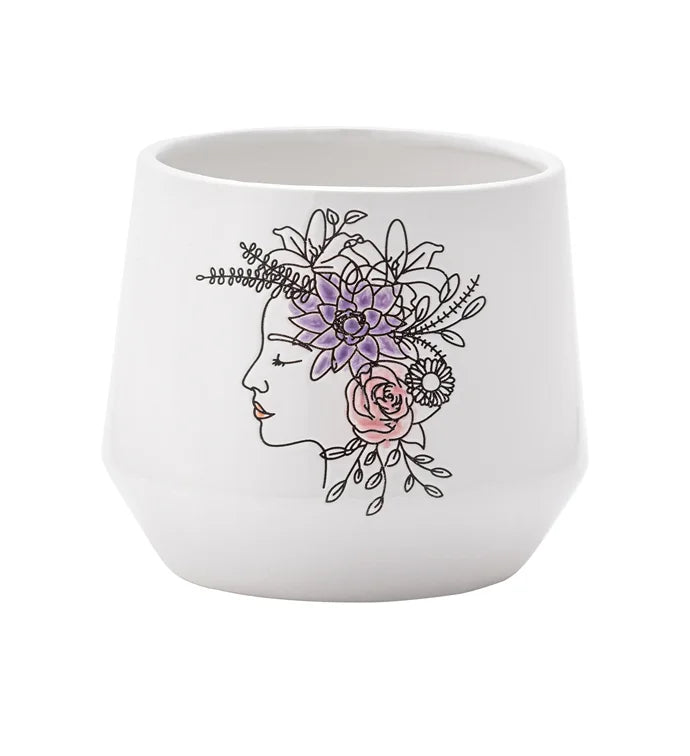 The Purple Flower Crown Ceramic Pot features a minimalist white design with a line-drawn woman's profile, accented by purple, pink, and green floral details—an elegant and artistic planter for any space.