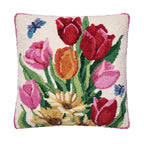 A square hand-tufted decorative pillow featuring a colorful floral design with red, pink, and orange tulips, green leaves, a cream daisy, and blue butterflies on an off-white background.