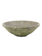 A rustic, handcrafted stone bowl with a textured, weathered finish in muted gray-green tones, isolated on a white background.