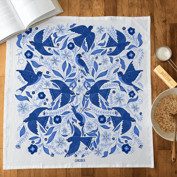 A cotton flour sack towel with an allover pattern featuring blue songbirds.